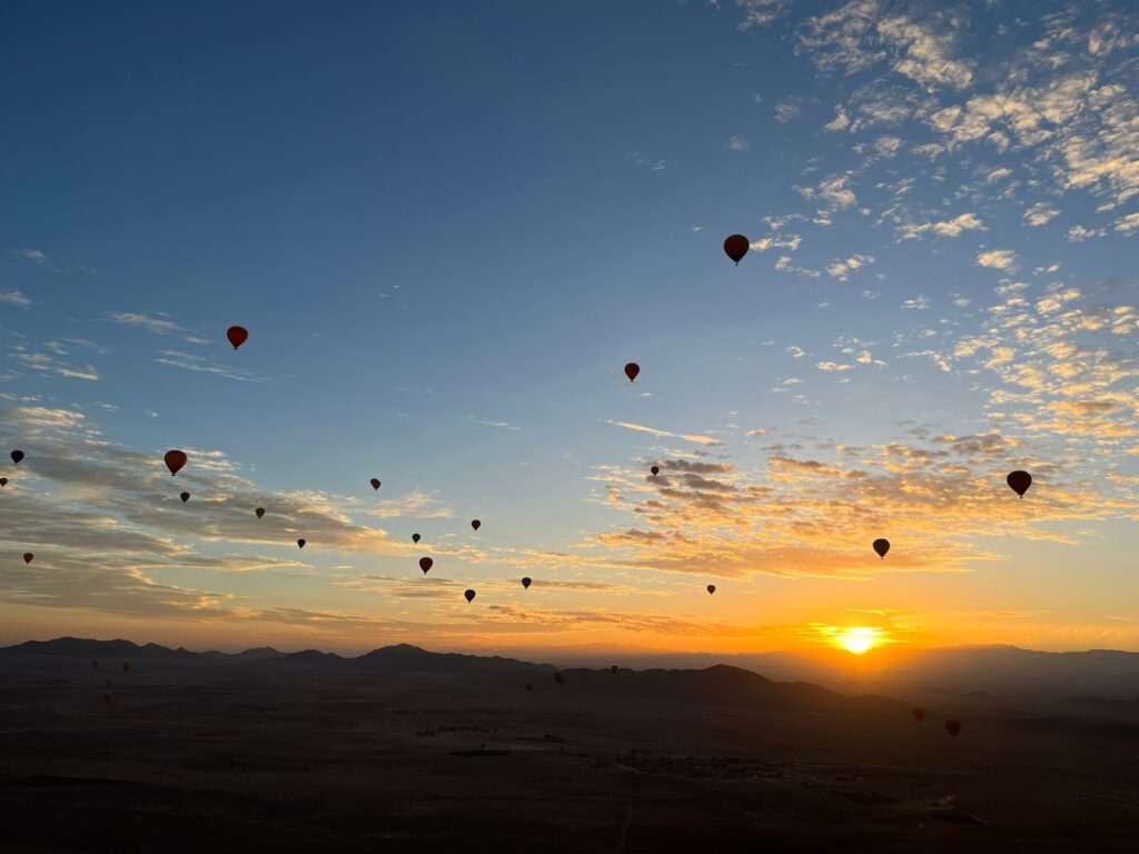 A Dozen Hot Air Balloons in Sky with Sunrise.