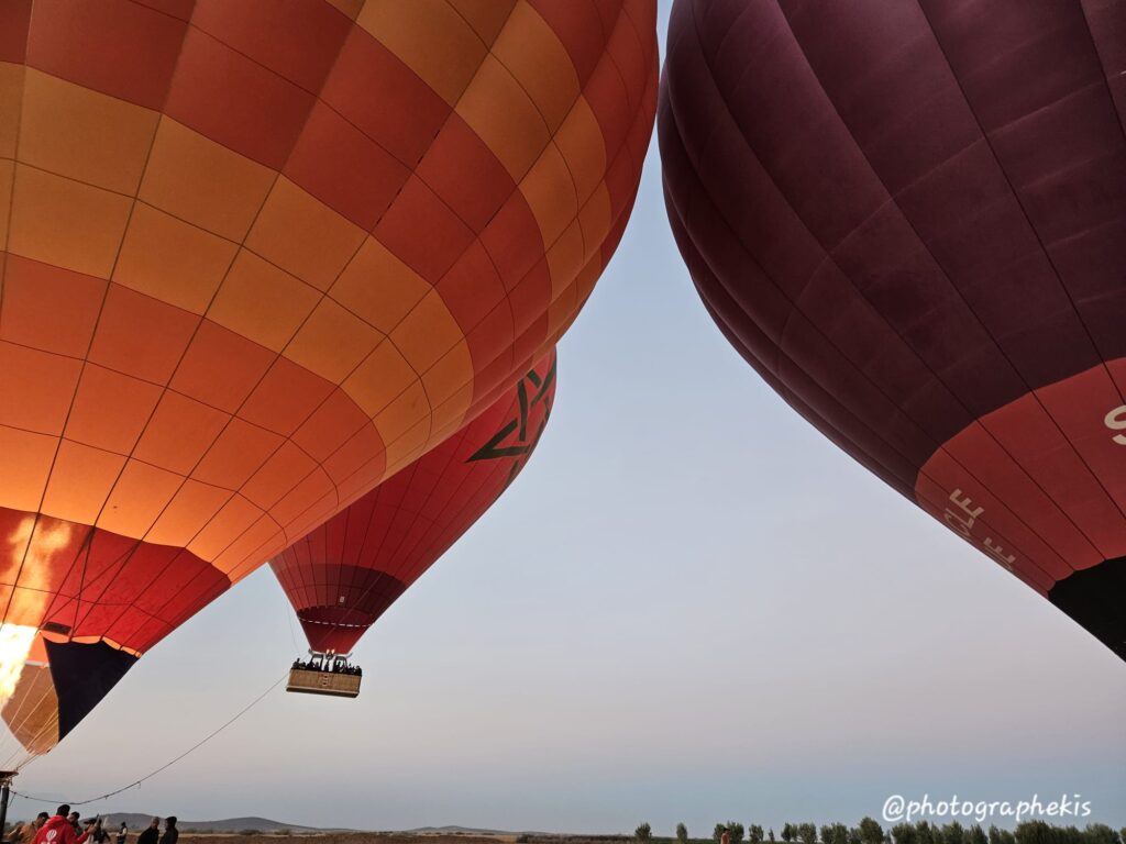 Trois montgolfieres décollent du sol et s'envolent.